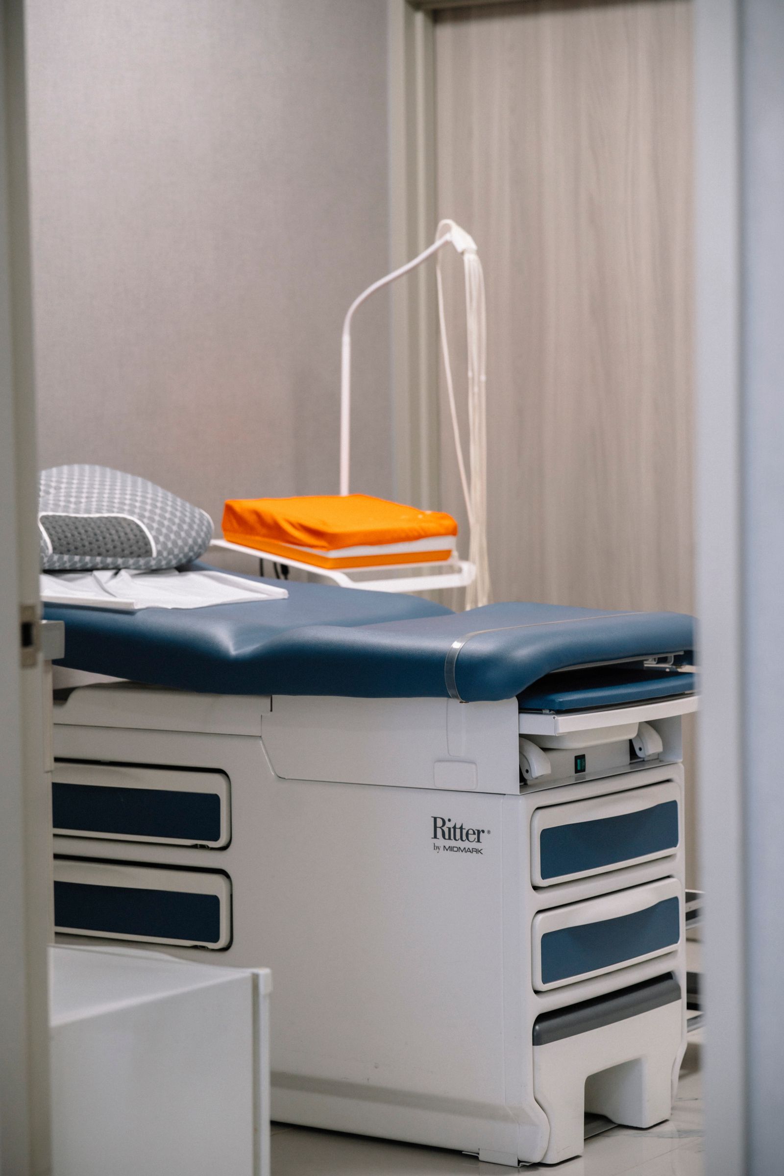 Clean and modern medical examination room with an examination table and neat furnishing.